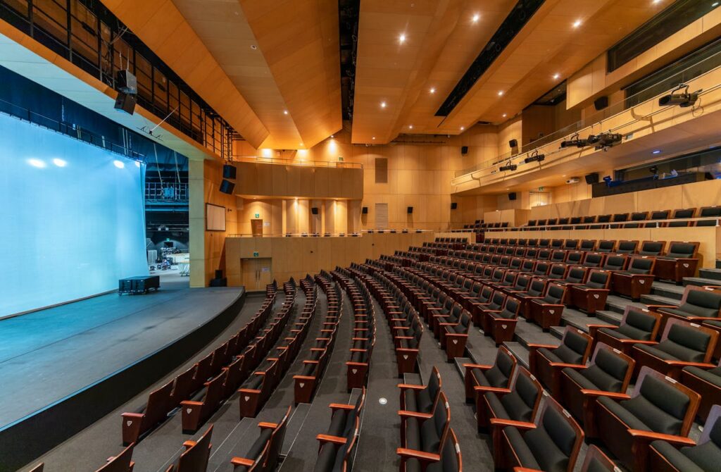 Spacious contemporary auditorium with empty seats and a stage, ideal for concerts or presentations.