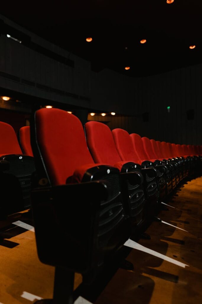 Rows of empty red cinema seats in a dimly lit theater, captured with a dramatic angle.